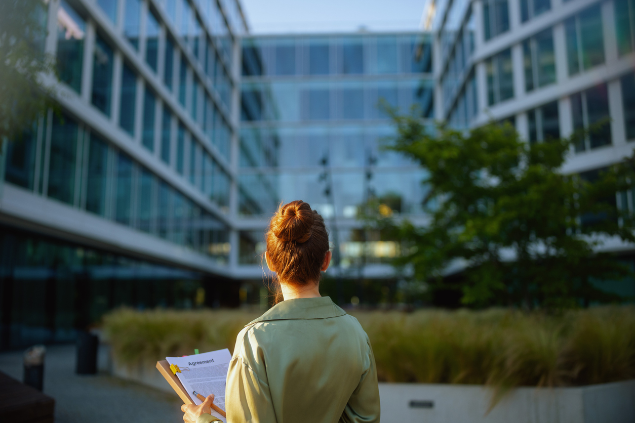 Client holding a financial agreement outside modern office buildings while considering Indexed Universal Life Insurance protection against market volatility